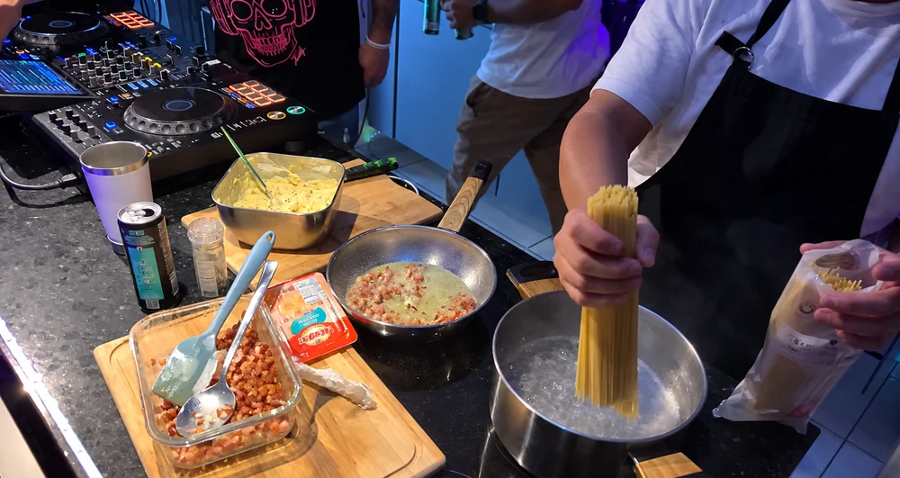 Preparo de massa na cozinha, ao lado do equipamento de DJ
